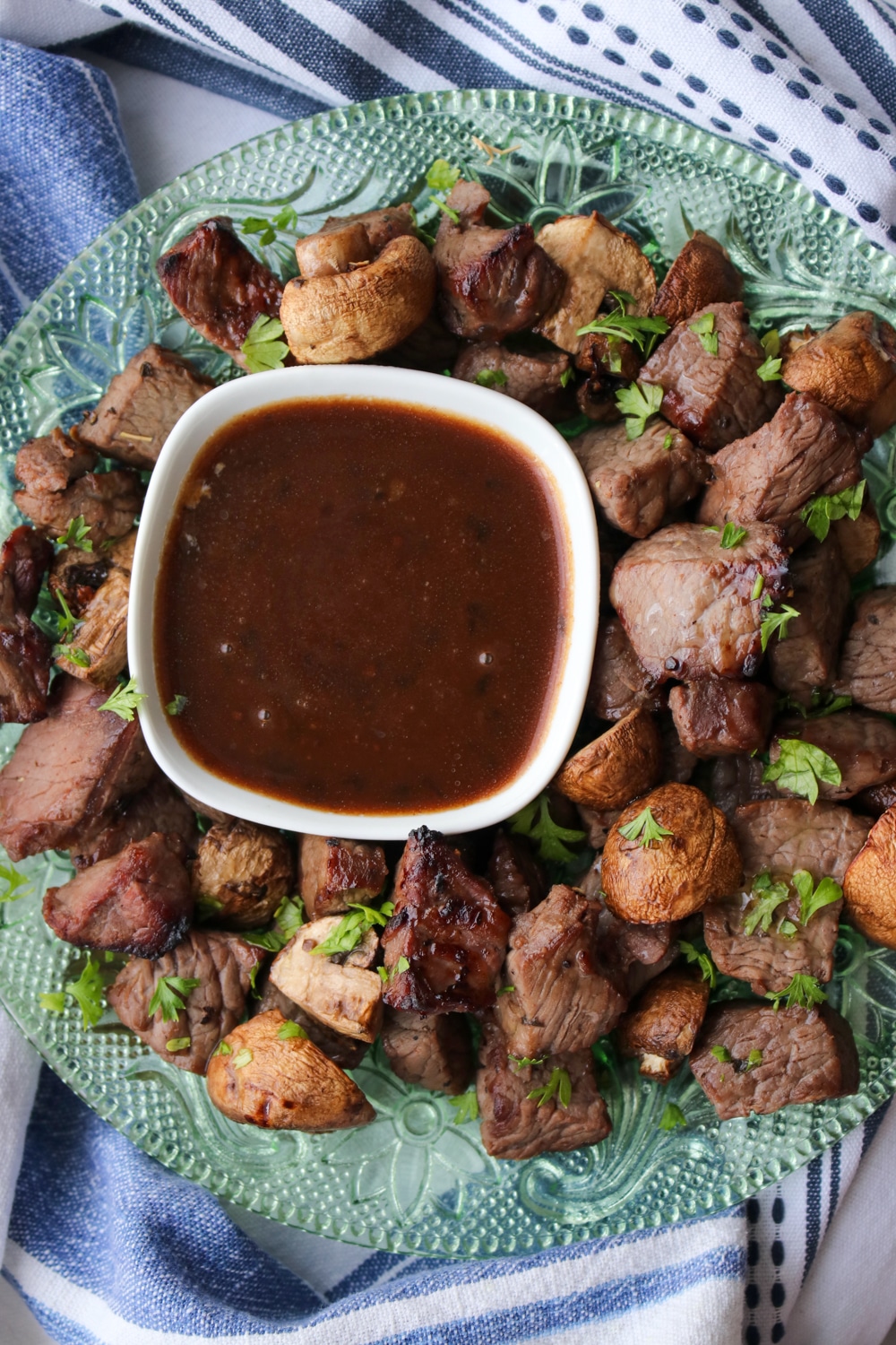 plate of steak and mushroom bites with a bowl of steak sauce in the middle