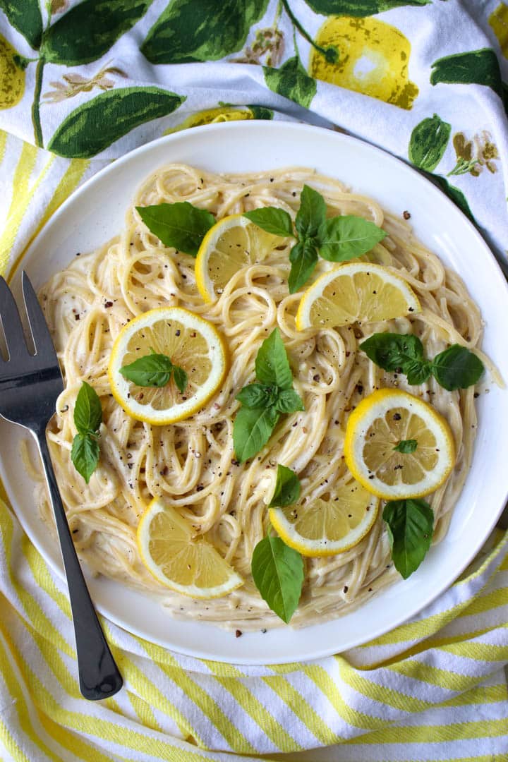 dish of lemon pasta with sliced lemons and fresh basil on top