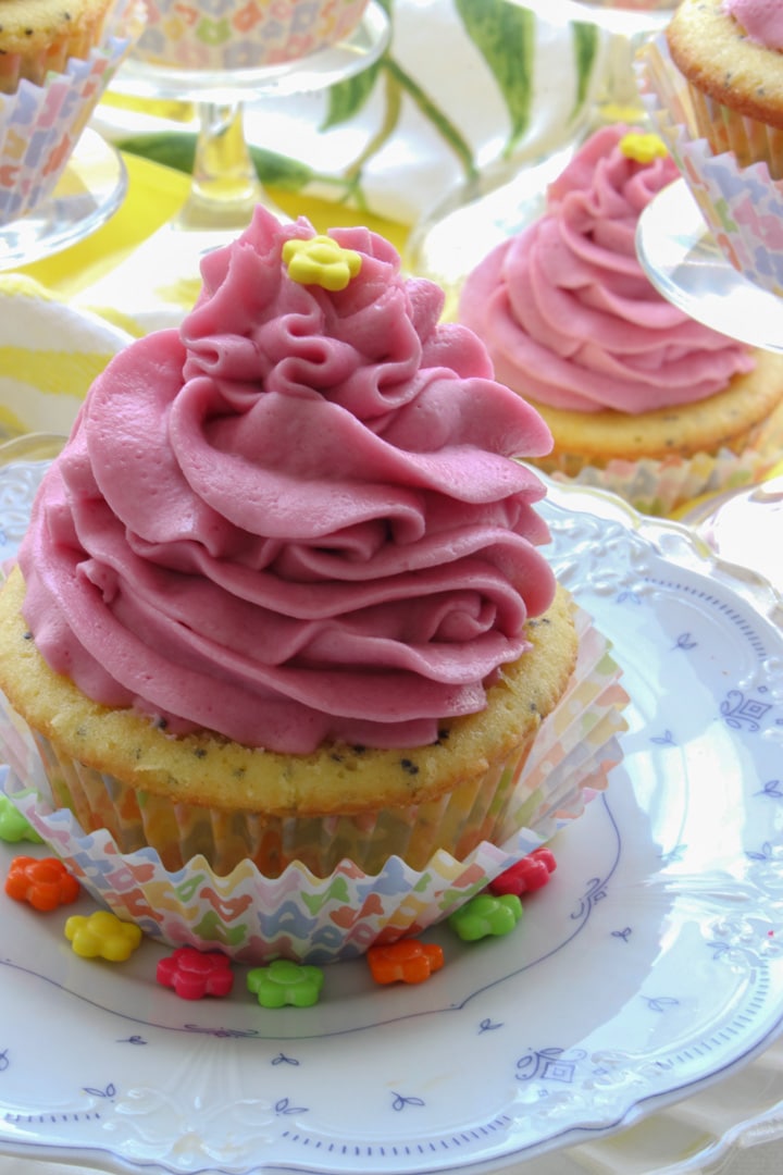 lemon cupcake with bright pink swirly frosting and a yellow candy on top.