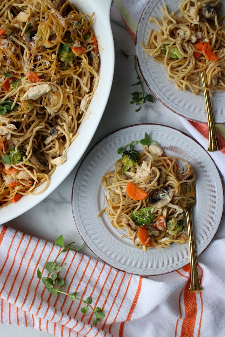 casserole dish and 2 servings of chicken tetrazzini on small plates with gold forks