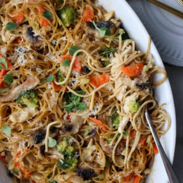 chicken tetrazzini pasta in a white baking dish with a fork full of pasta