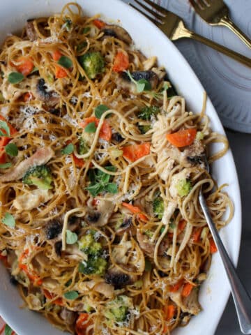 chicken tetrazzini pasta in a white baking dish with a fork full of pasta