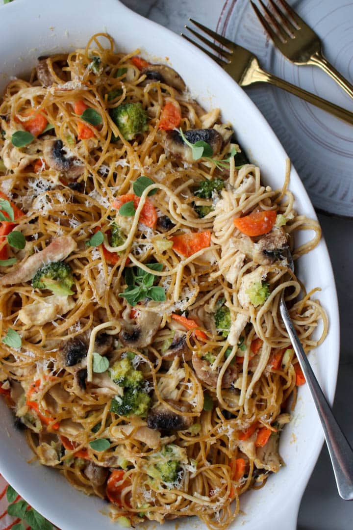 chicken tetrazzini pasta in a white baking dish with a fork full of pasta