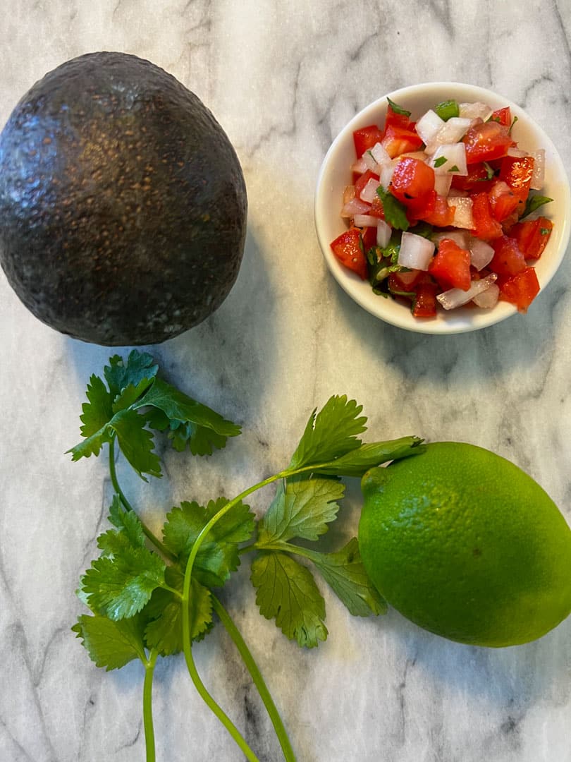 avocado, cilantro, lime, pico de gallo on a marble table