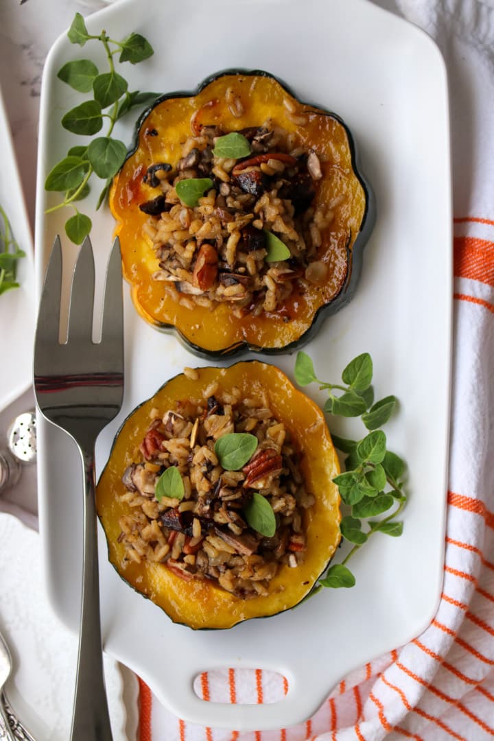 white platter with two acorn squash stuffed with wild rice