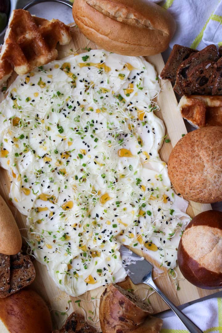 butter, honey, sprout spread on a board surrounded by assorted breads