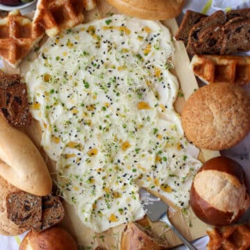 butter, honey, sprout spread on a board surrounded by assorted breads