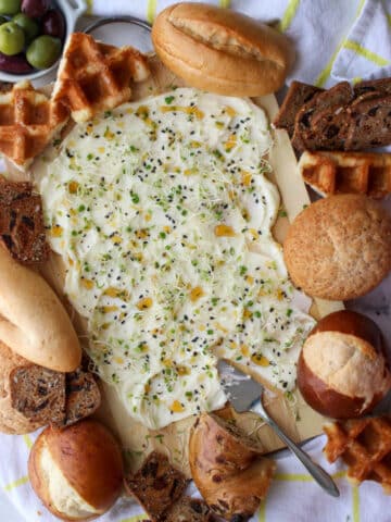 butter, honey, sprout spread on a board surrounded by assorted breads