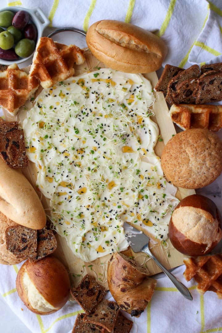 butter, honey, sprout spread on a board surrounded by assorted breads