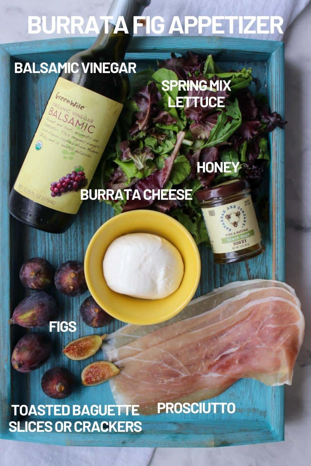 blue wooden tray with ingredients to make burrata fig appetizer