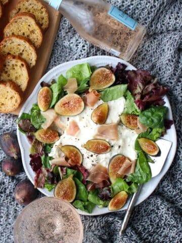 platter of burrata cheese, mixed greens, and sliced figs with toast crisps and champaign