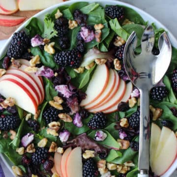 bowl of greens with berries and sliced apples