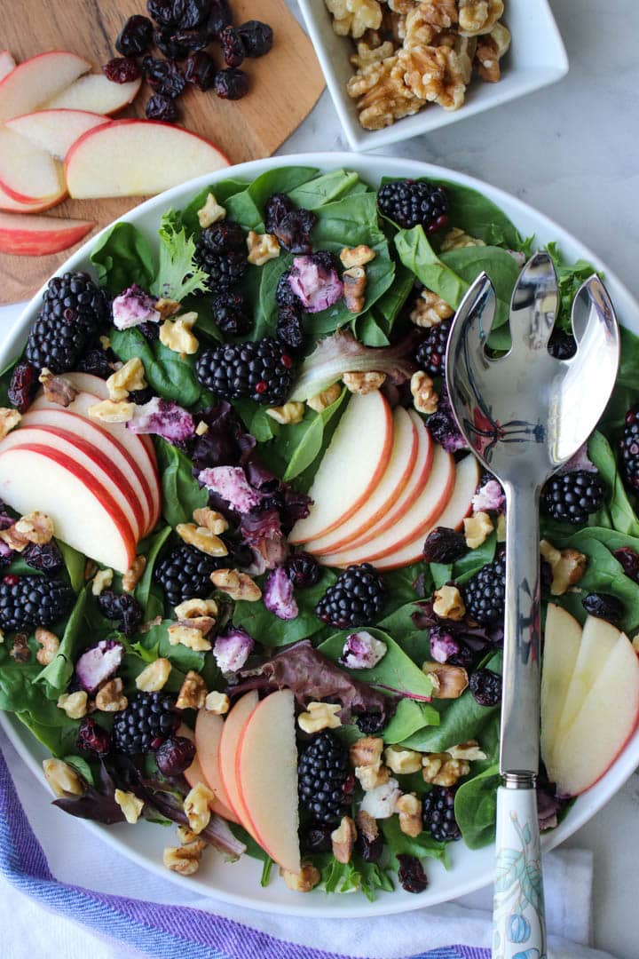 bowl of greens with berries and sliced apples