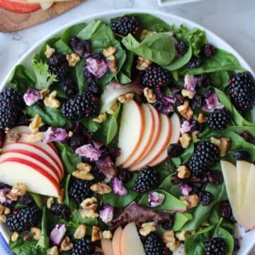platter of mixed greens, apple slices, berries and goat cheese