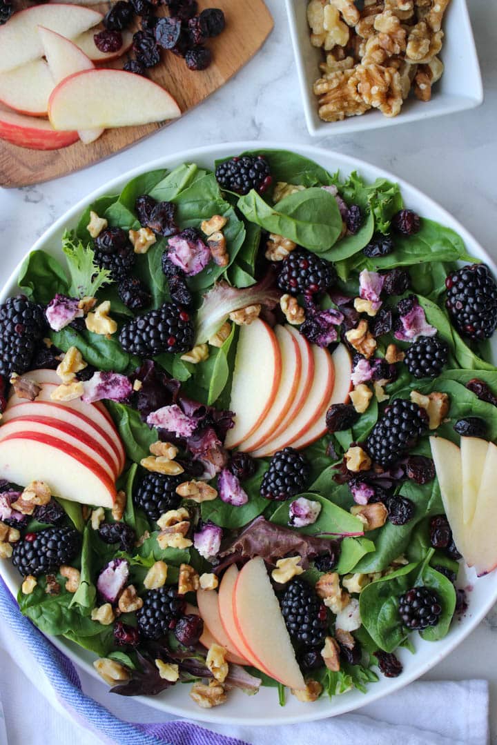 platter of mixed greens, apple slices, berries and goat cheese