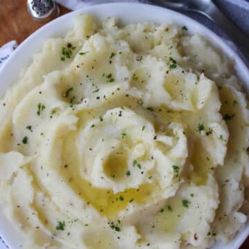 large bowl of mashed potatoes with butter and parsley