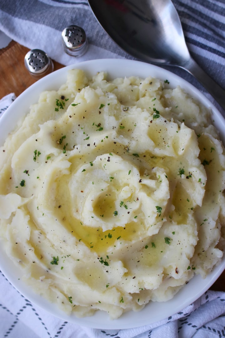 large bowl of mashed potatoes with butter and parsley