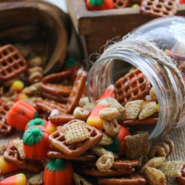 pumpkin pie spice party mix spilling out of tipped over jar