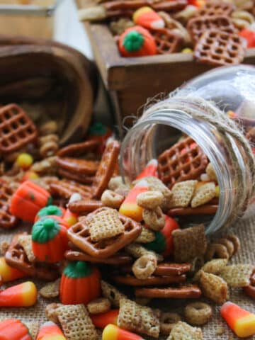 pumpkin pie spice party mix spilling out of tipped over jar