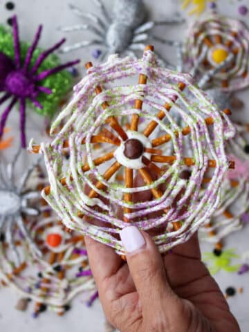 women's hand holding spider web pretzels