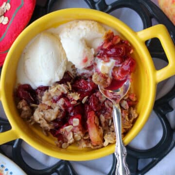 yellow bowl with handles with cranberry apple crisp and 2 scoops of ice cream