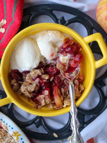 yellow bowl with handles with cranberry apple crisp and 2 scoops of ice cream
