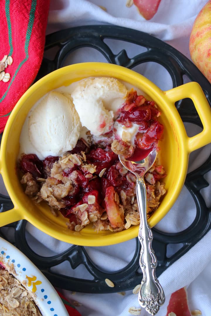 yellow bowl with handles with cranberry apple crisp and 2 scoops of ice cream