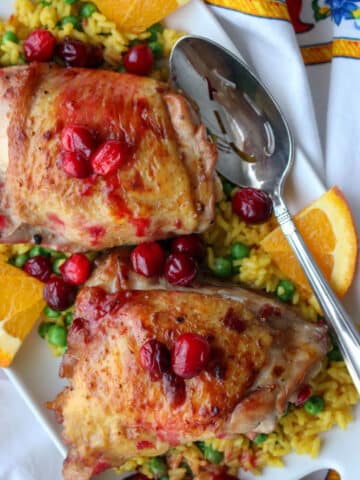 platter with yellow rice and peas topped with bake cranberry chicken