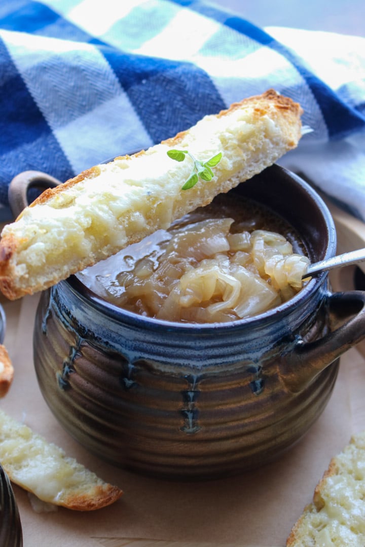 bowl of french onion soup with a slice of cheese bread balancing on the rim