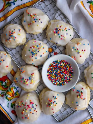 Italian wedding cookies on a rack with a bowl of sprinkles