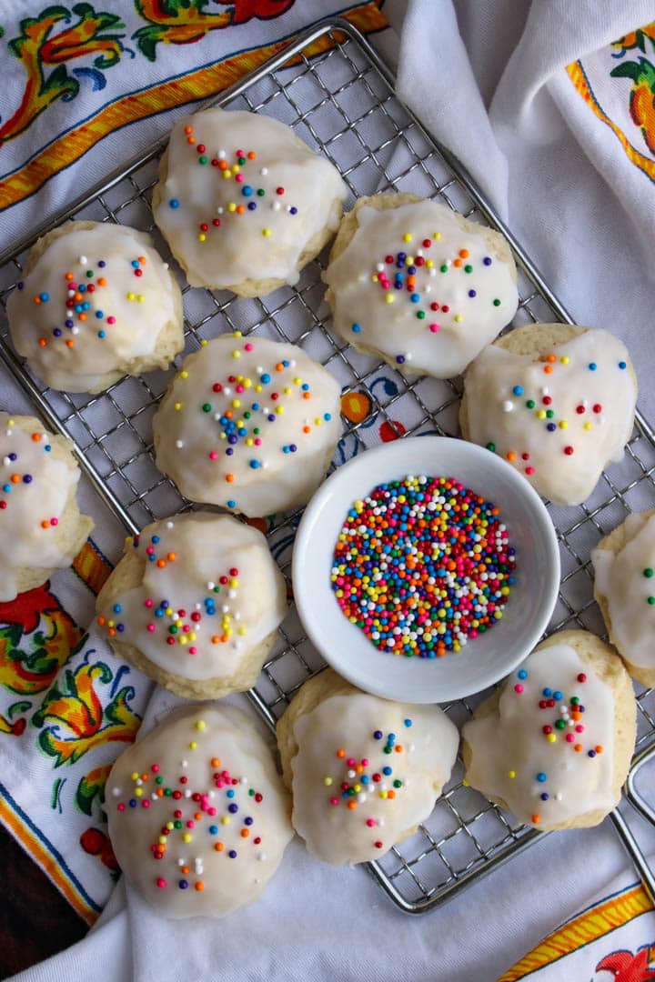 Italian wedding cookies on a rack with a bowl of sprinkles