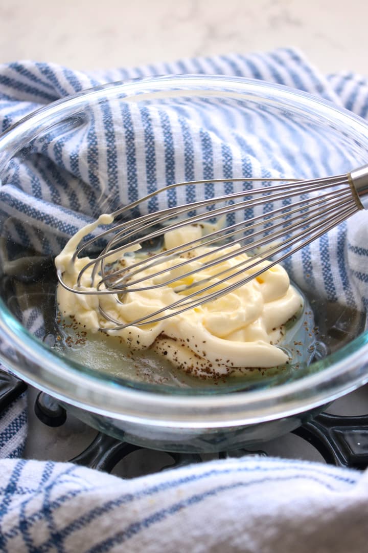 Ingredients to make Waldorf salad dressing in a glass bowl with a whisk