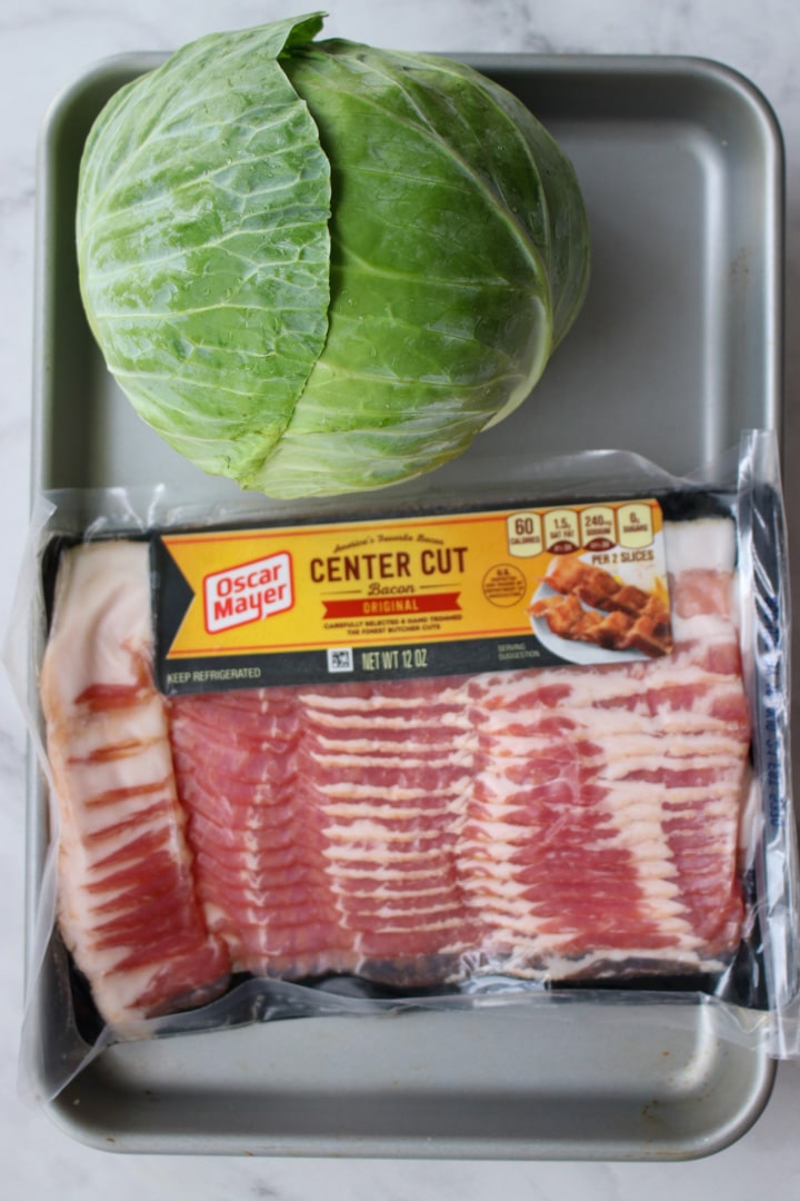 head of green cabbage and a pound of bacon on a cookie sheet