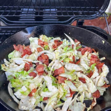 skillet of bacon and cabbage on a bbq gas grill