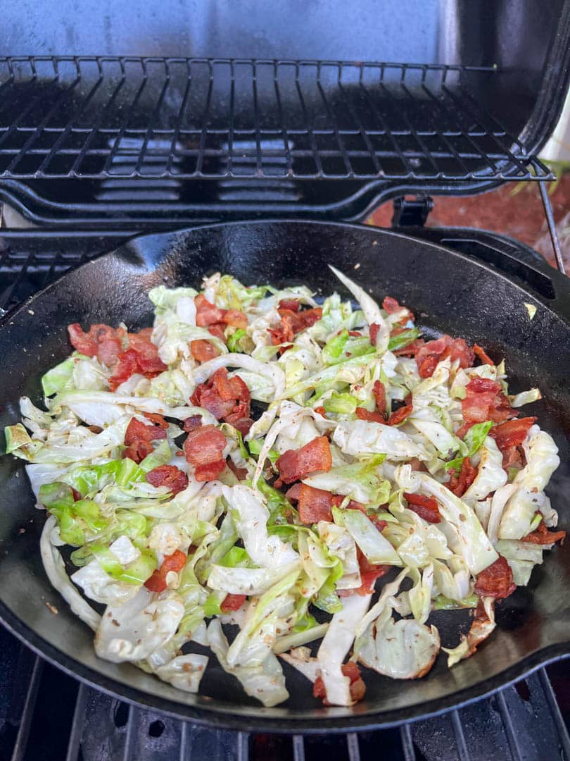 skillet of bacon and cabbage on a bbq gas grill