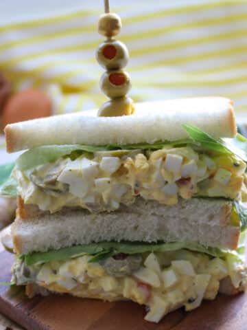 egg salad sandwich with a skewer of green olives stuck into it