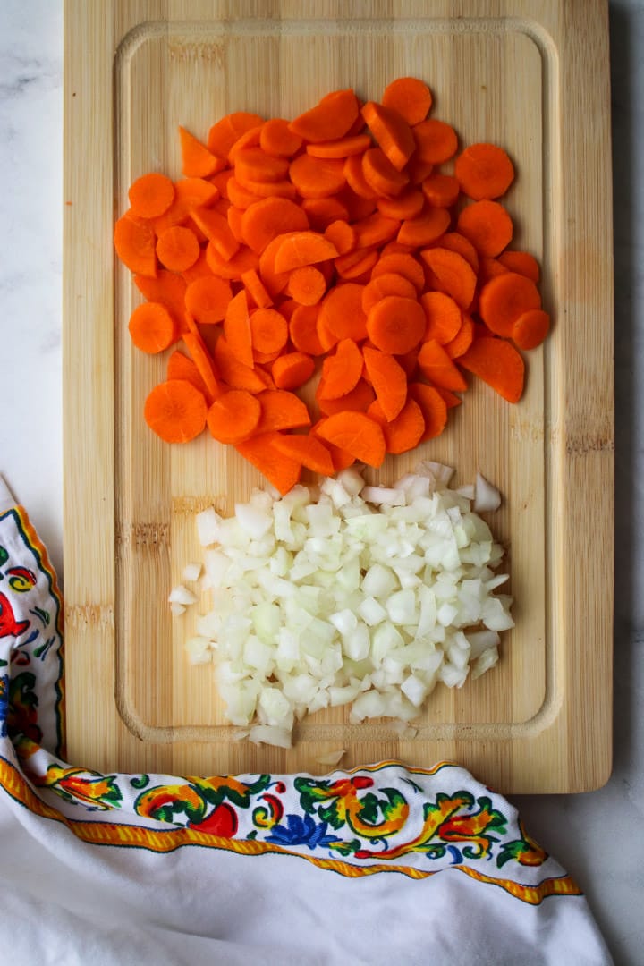 cutting board with sliced carrots and diced onions