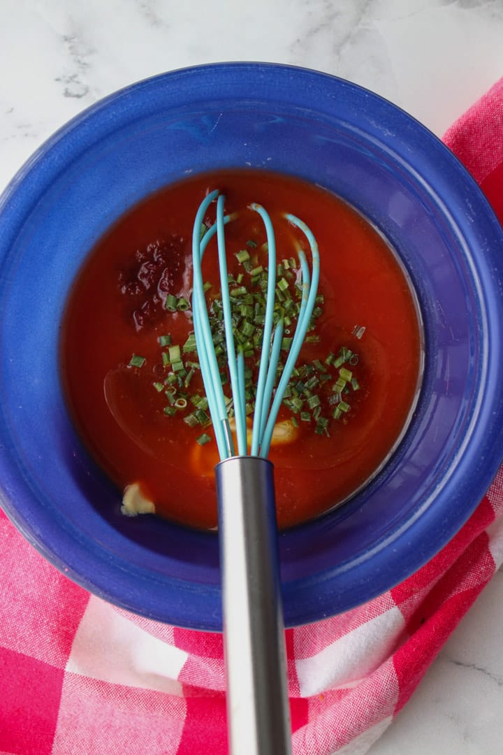 bowl with ingredients to make tomato vinaigrette with a whisk