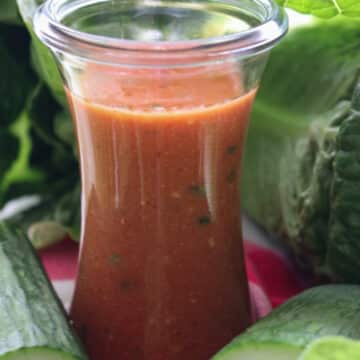 jar of tomato salad dressing and salad greens