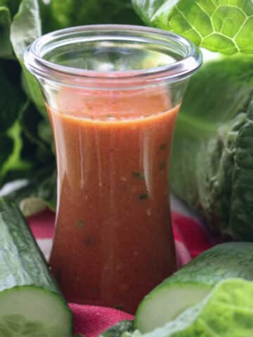 jar of tomato salad dressing and salad greens