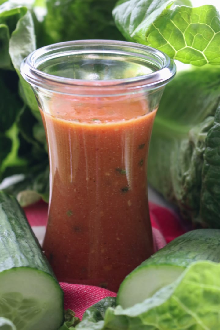 jar of tomato salad dressing and salad greens