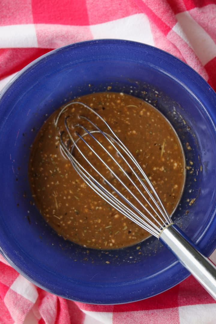 blue bowl with balsamic dressing and a large whisk