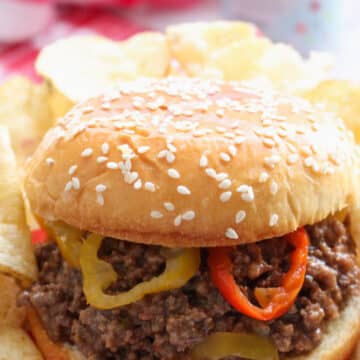 SLOPPY JOE ON SESAME SEED BUD GARNISHED WITH BANANA PEPPERS