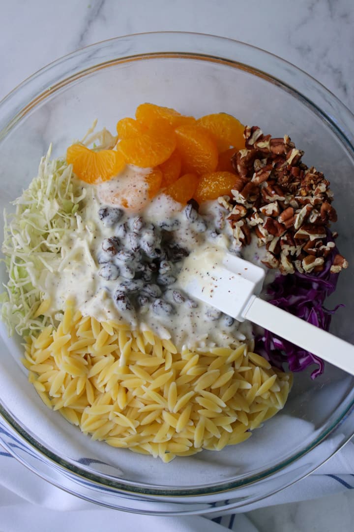 bowl of orzo coleslaw with dressing on top