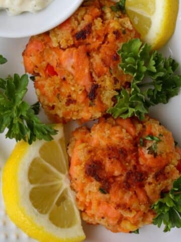 close up shot of two salmon patties on a white plate