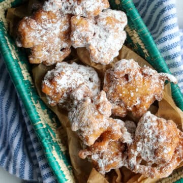 fritters dusted with powdered sugar in a green basket