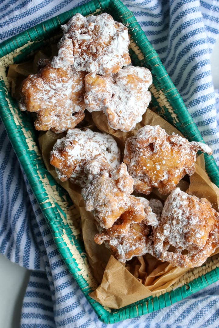 fritters dusted with powdered sugar in a green basket