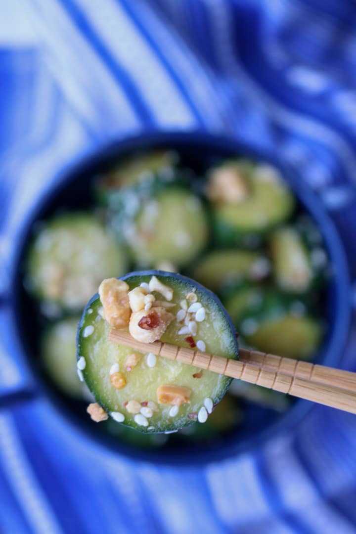 chop sticks holding 1 cucumber slice