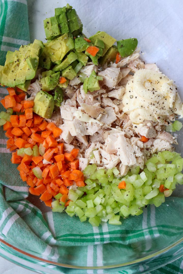 bowl with diced chicken, diced carrots, diced celery, diced avocado, and mayonnaise