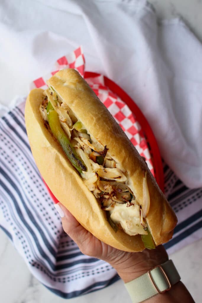 Woman's hand holding a cheesesteak hoagie